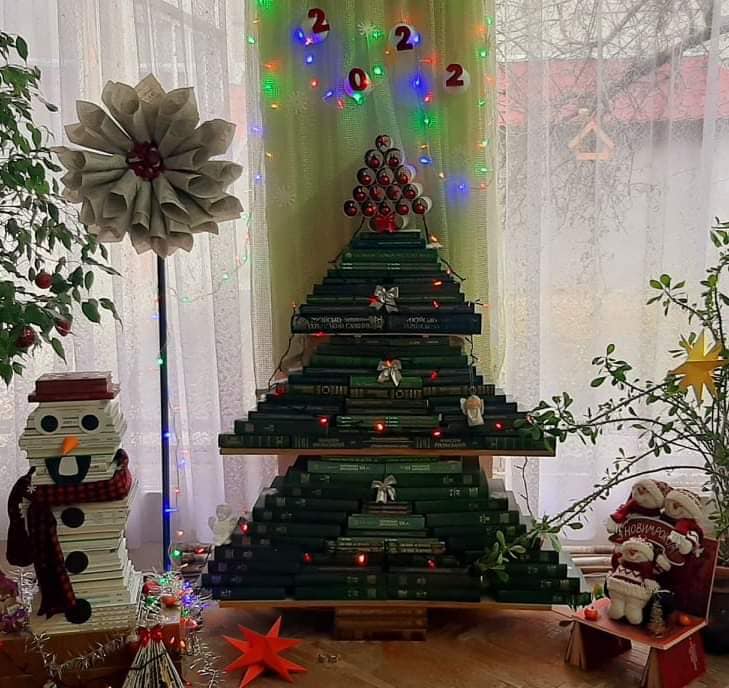 Творческая новогодняя елка в том, что она сделана из книг, а также снеговик.